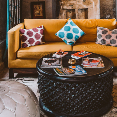 Dark mustard leather couch with three accent pillows with a black round coffee table.